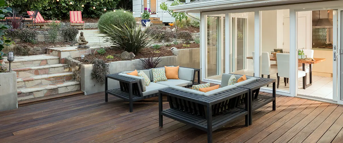 outdoor retreat wooden deck with white and black sofas orange pillows
