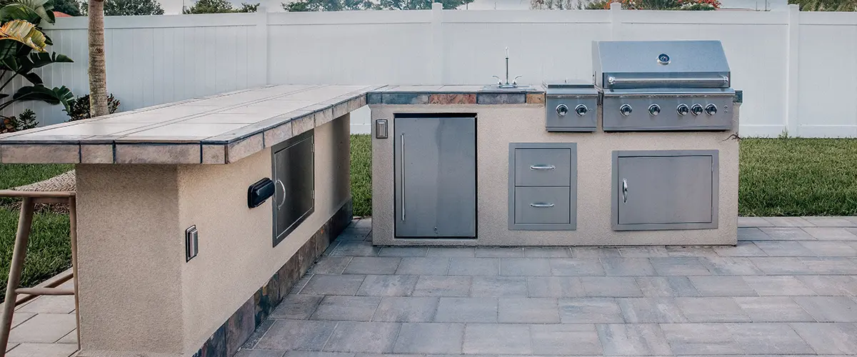 An outdoor kitchen with a smoker and a refrigerator