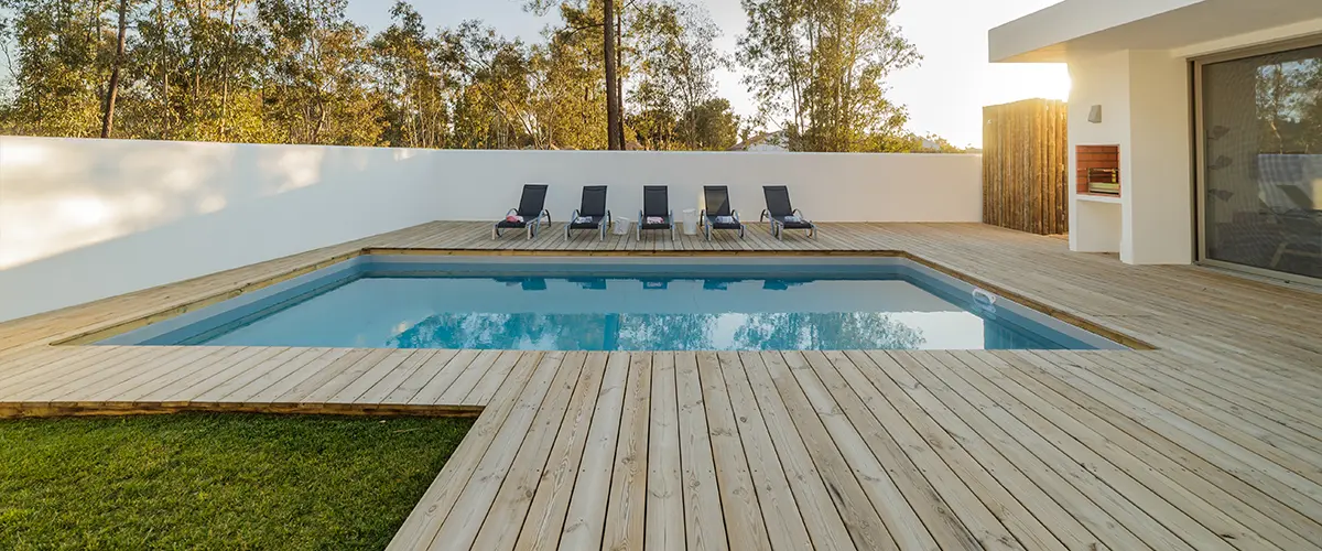 Wood decking around a pool with long chairs