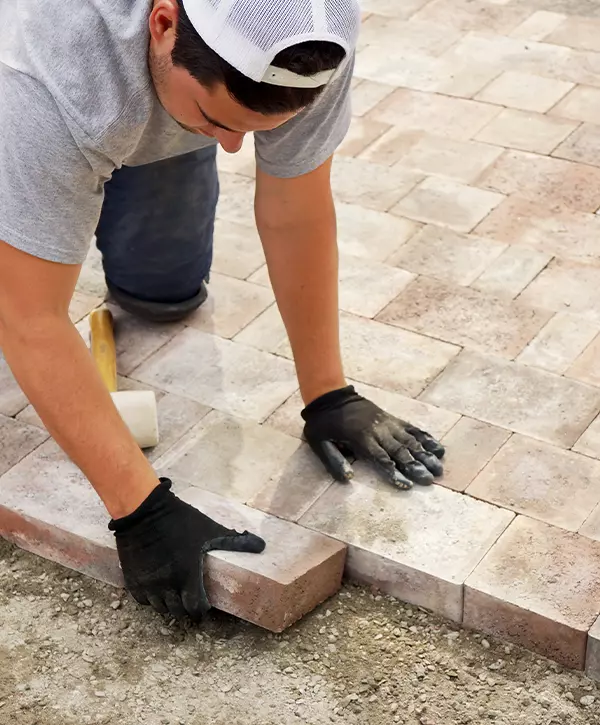 Worker installing Paver stone landscaping, best paver patios in Lewisville, TX