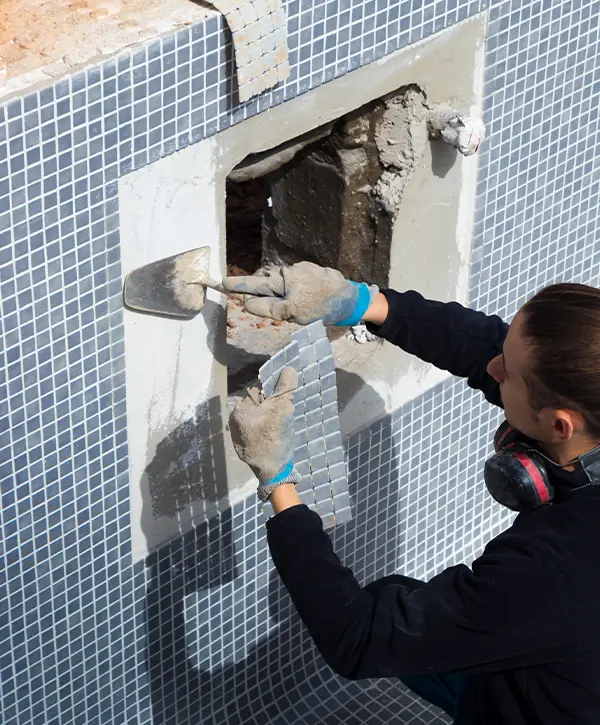 man working as a laborer in a swimming pool work putting tiles