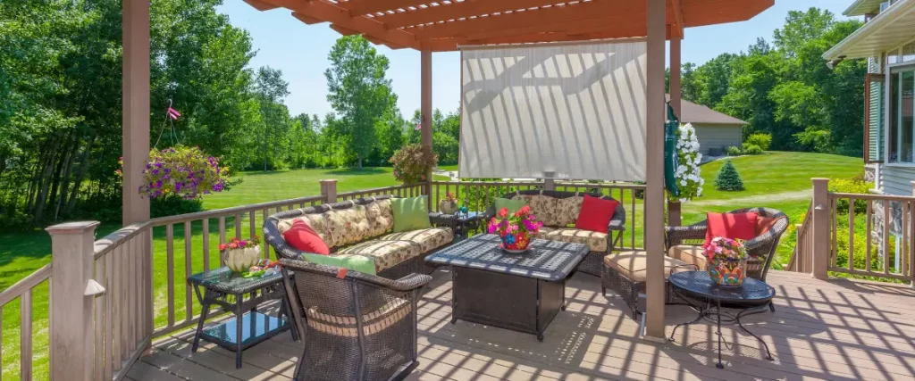 A cozy deck with a pergola, outdoor seating, vibrant cushions, and a privacy screen, surrounded by lush greenery