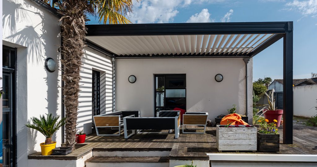 Modern backyard patio with aluminum pergola and slatted roof providing shade over outdoor furniture