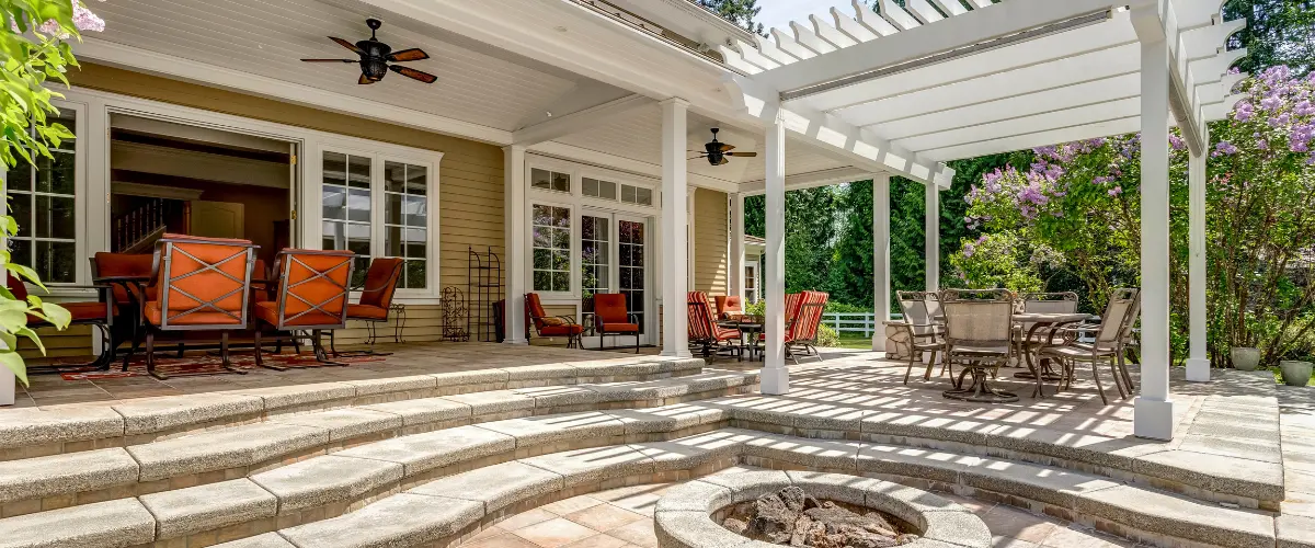 Hardscaped patio with stone steps, fire pit, and pergola