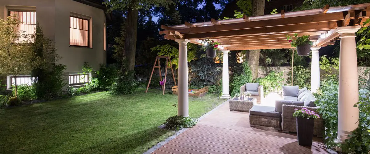 Custom backyard gazebo with columns, outdoor seating, wood pergola roof, and ambient lighting for cozy evening entertainment.