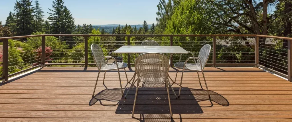 Modern composite deck with cable railing and metal patio furniture overlooking lush trees and scenic views