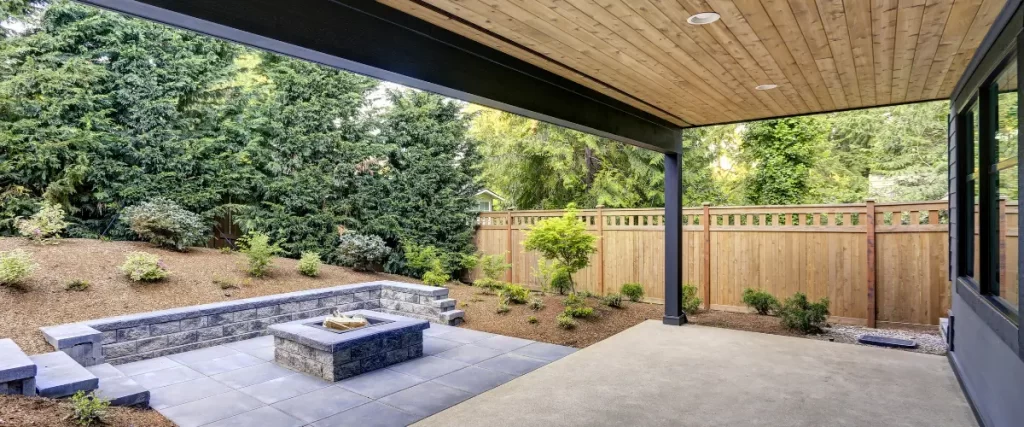 Covered patio with stone fire pit and landscaped yard
