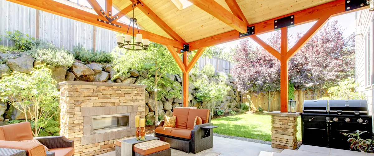 Covered patio with wood beams, fireplace, and grill area