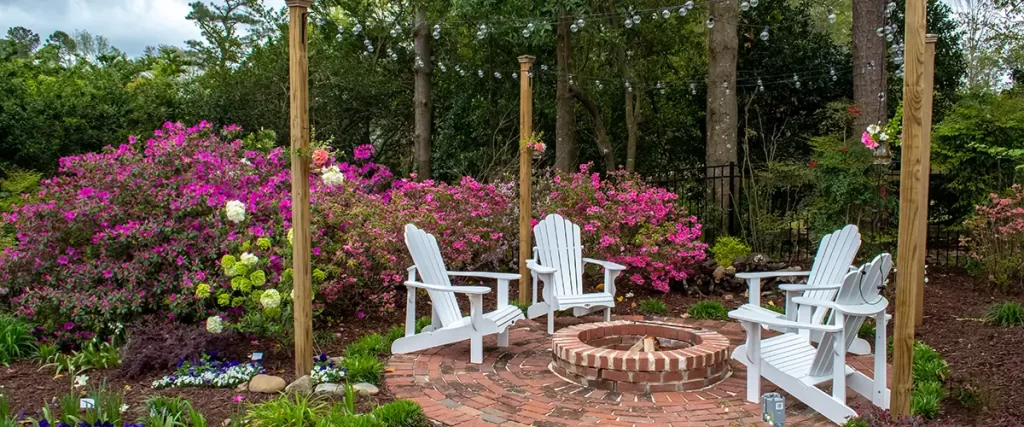 Brick patio with white Adirondack chairs and built-in fire pit
