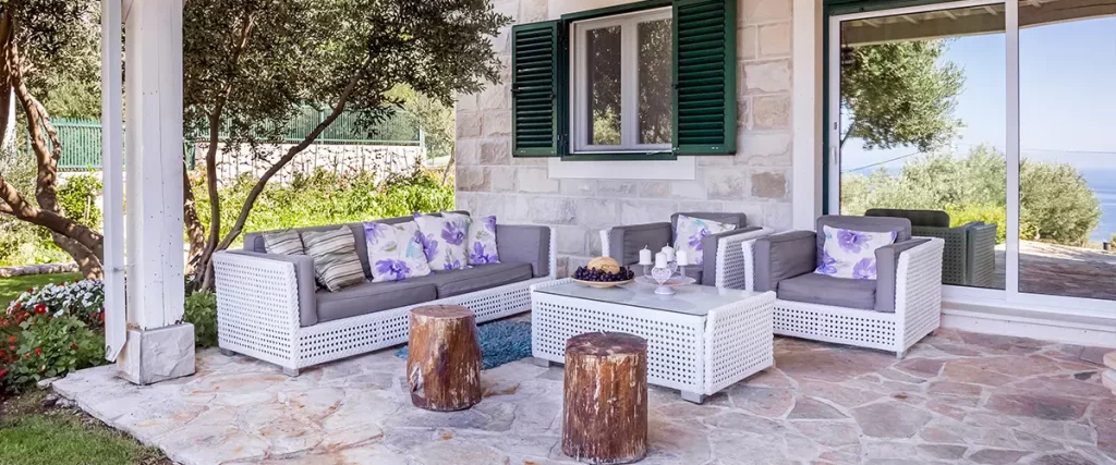 Covered stone patio with wicker furniture and garden view