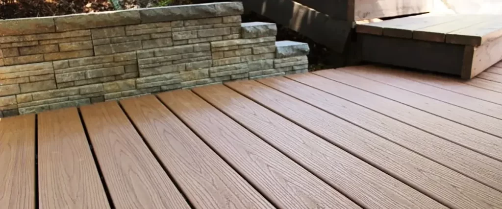 Brown Trex composite deck next to a stone retaining wall
