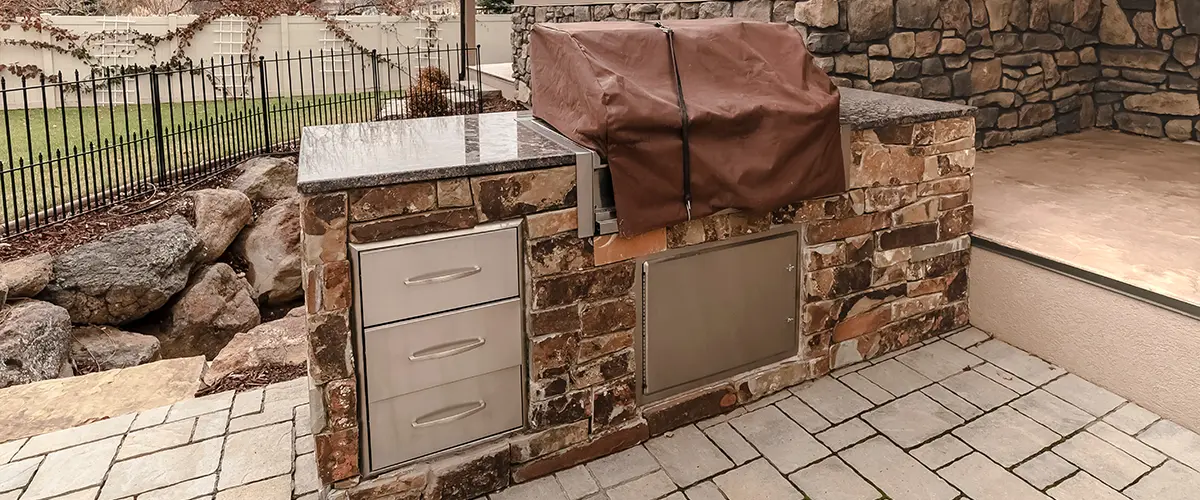 Stone outdoor kitchen with built-in grill and stainless storage