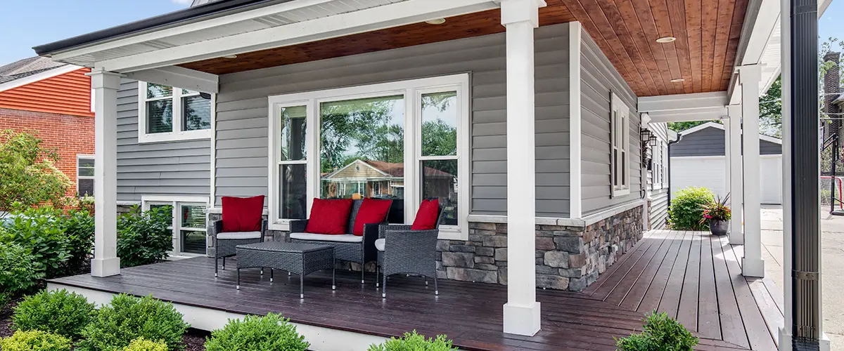 Modern front porch with white columns and red-cushioned patio furniture