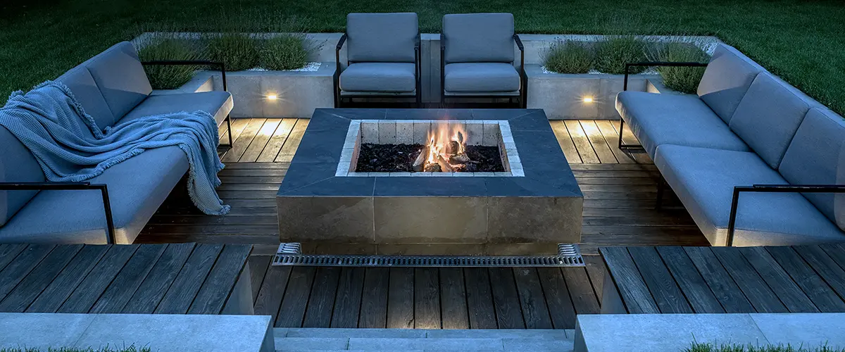 Modern sunken fire pit seating area with evening lighting