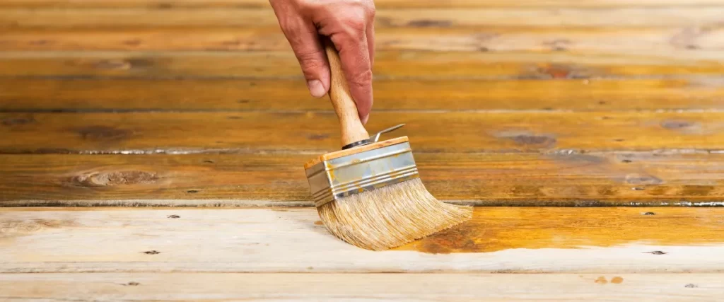 Applying wood stain with a brush on a deck surface