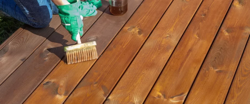 Staining wooden deck boards with a wide brush