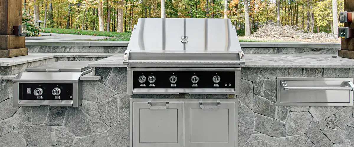 Outdoor kitchen with stainless steel grill and stone countertop setup