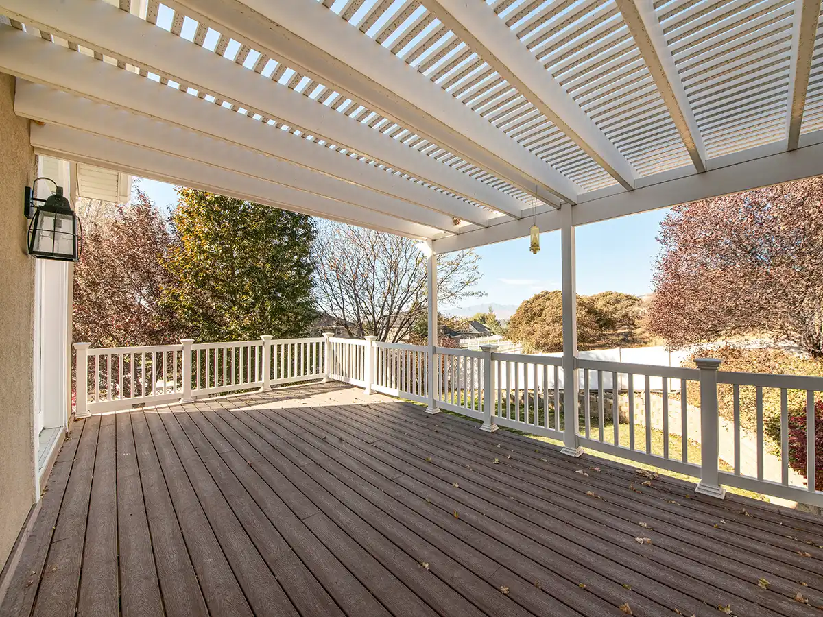 White pergola covering composite deck with railing and open view