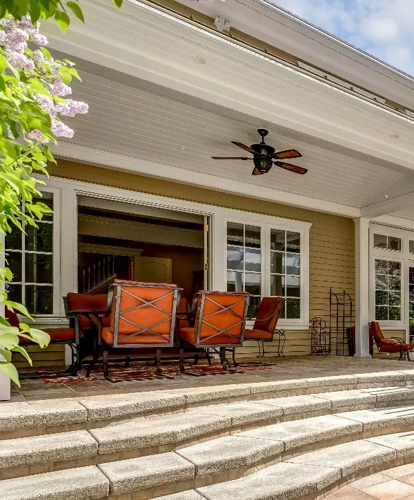 A covered patio featuring a large table surrounded by several chairs, ideal for outdoor dining and gatherings.