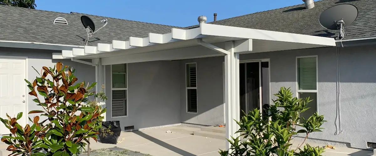 A house featuring a covered patio, surrounded by greenery and outdoor furniture for relaxation.