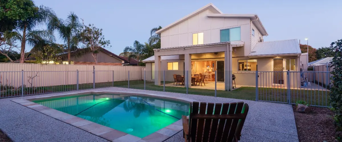 A modern home featuring a pool and a spacious patio area, surrounded by greenery