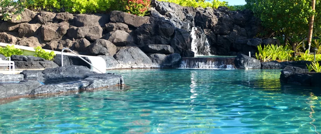 pool spa installation texas aqua blue pool with waterfall surrounded by lush greenery and rocks