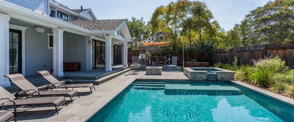 a luxury backyard featuring an in-ground swimming pool and hot tub.