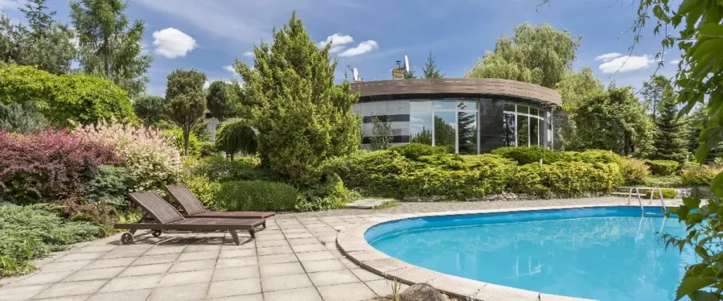 a modern detached house with a swimming pool in a landscaped backyard garden.