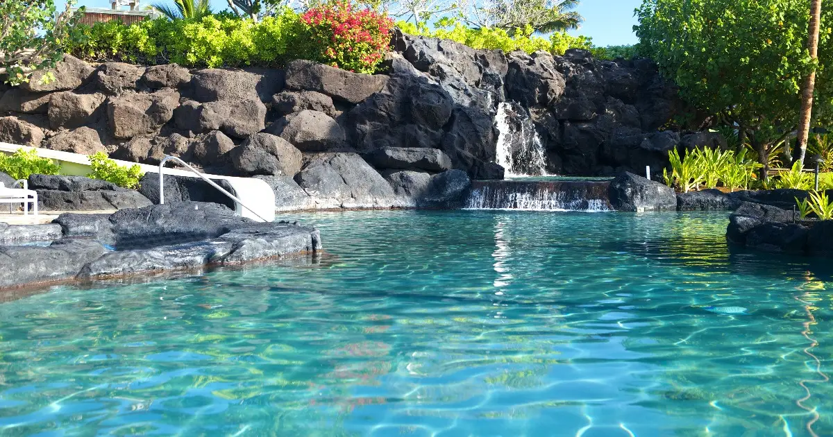 a swimming pool with a rock grotto and waterfall feature
