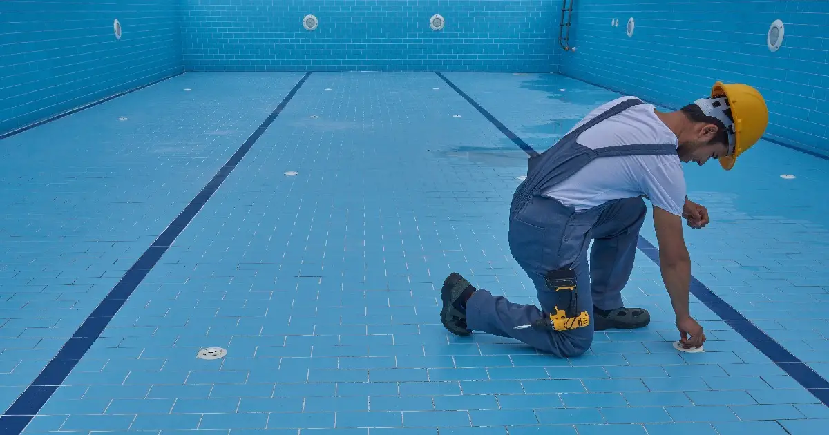 a worker installing or repairing the lining of an empty swimming pool