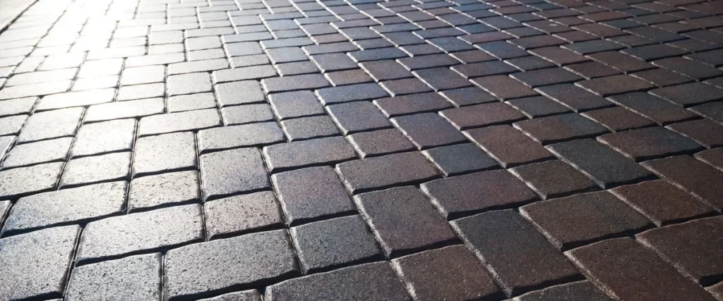 Close-up view of interlocking brick pavers with a high-gloss protective finish reflecting sunlight.