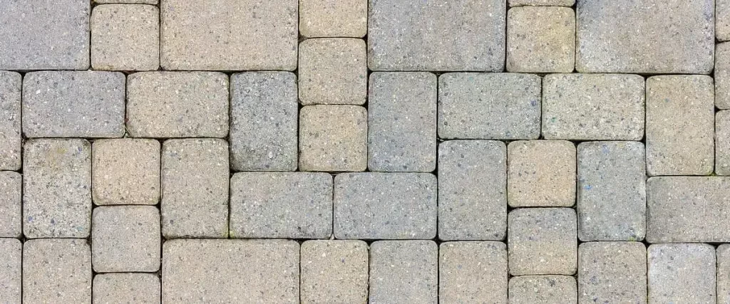Top-down view of durable interlocking concrete driveway pavers in a variety of neutral earth tones and textured stone patterns.