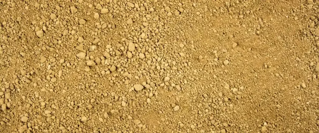 Top-down view of natural golden-tan decomposed granite material showing a mixture of fine silt and small crushed rock particles used for stable garden pathways and landscaping.