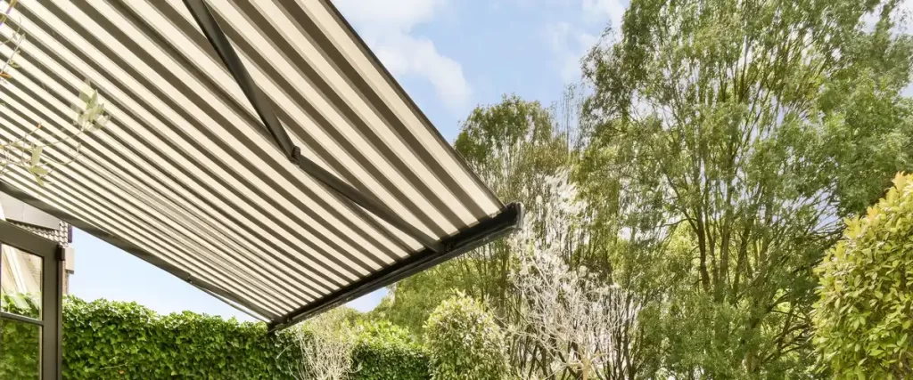 A black and white striped retractable awning extended over a patio to provide adjustable shade and UV protection.