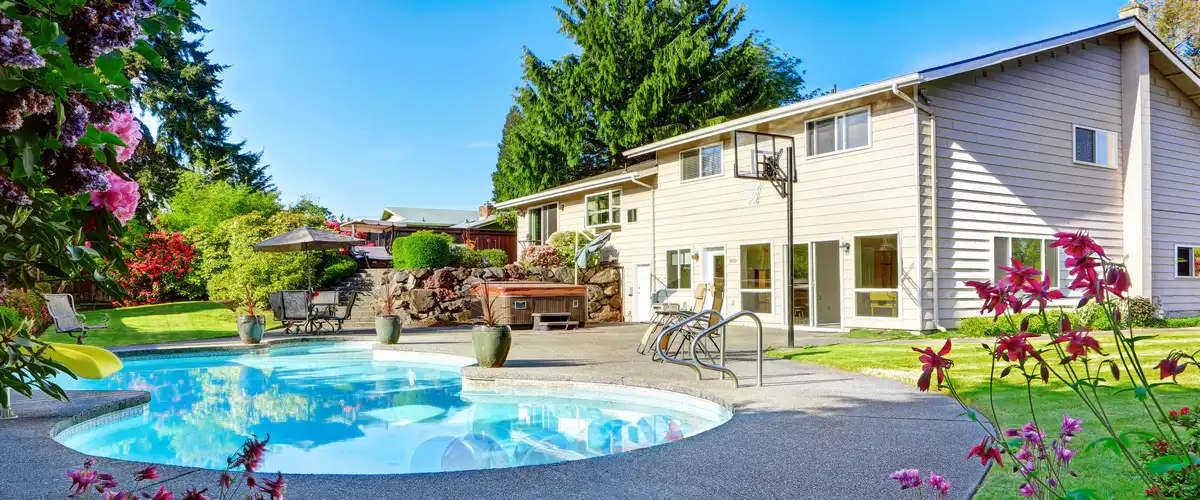 A backyard relaxation area featuring a clean swimming pool and a sun-drenched patio lounge.