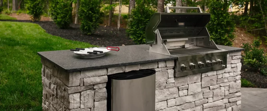 A spacious backyard entertainment area showcasing a complete outdoor kitchen setup next to a dining table.