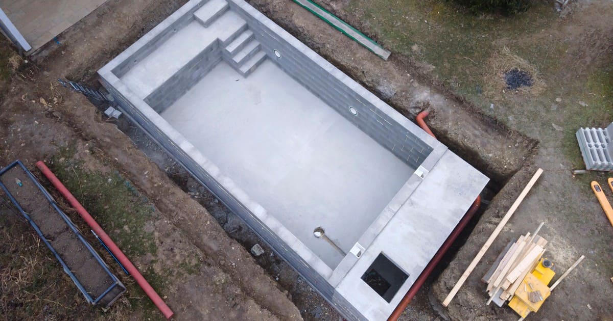 A luxurious modern backyard swimming pool with an integrated spa and patio lounge chairs, illustrating how to finance a pool project.