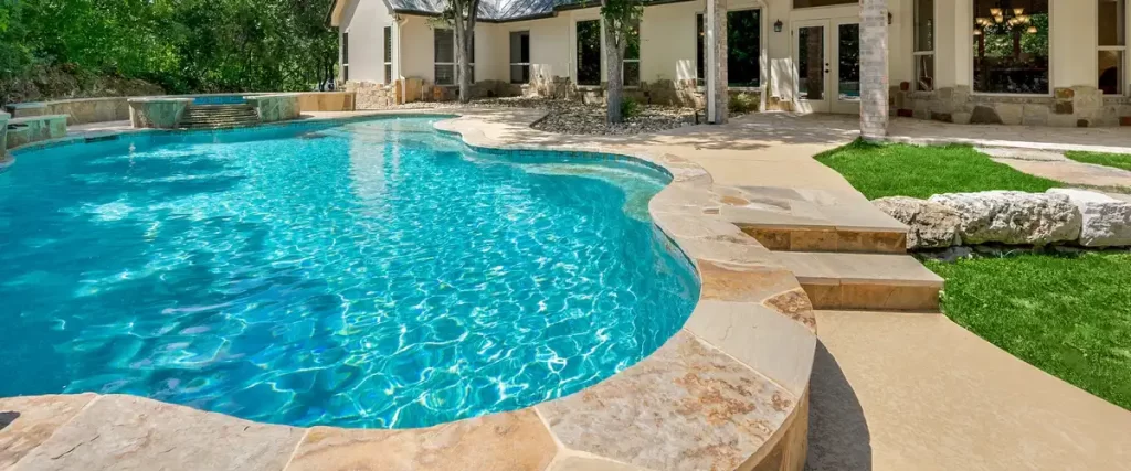 A stunning home swimming pool at sunset featuring warm underwater lighting, comfortable patio furniture, and a poolside pergola.