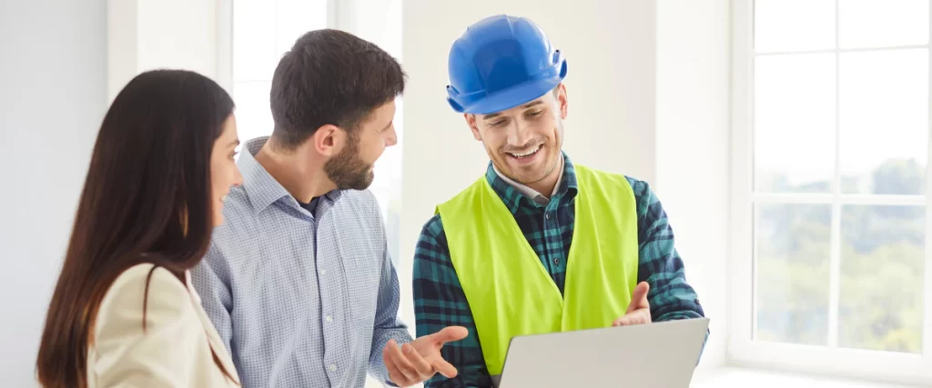 A professional contractor wearing a hard hat and safety vest examining architectural blueprints on a busy construction site.