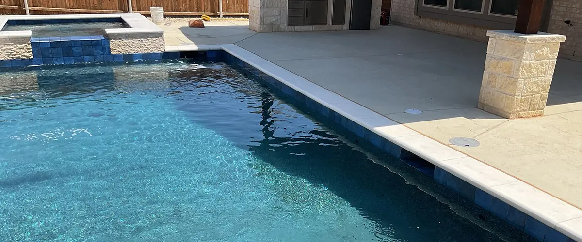 Modern backyard pool and spa with custom outdoor kitchen and stamped concrete patio