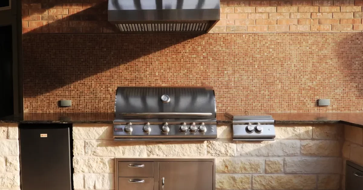 Stone outdoor kitchen with stainless steel grill and drawers