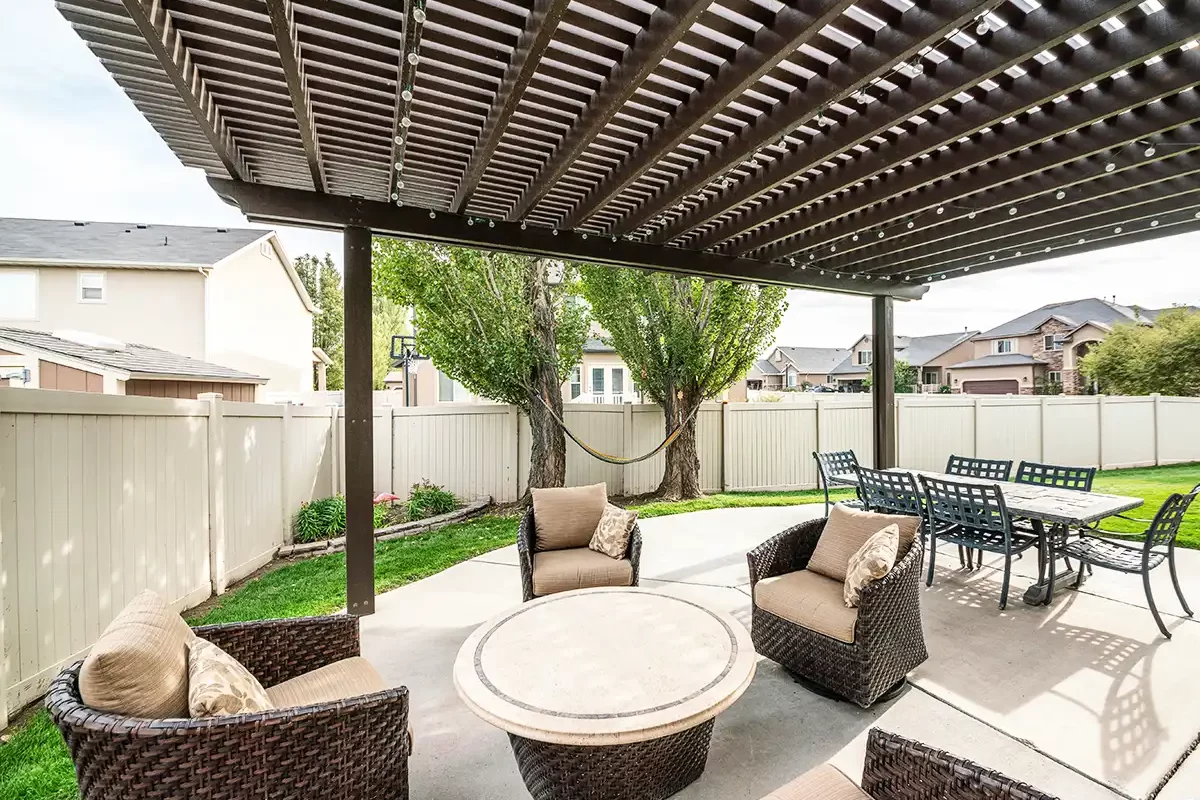 Backyard patio with dark wood pergola and outdoor seating area