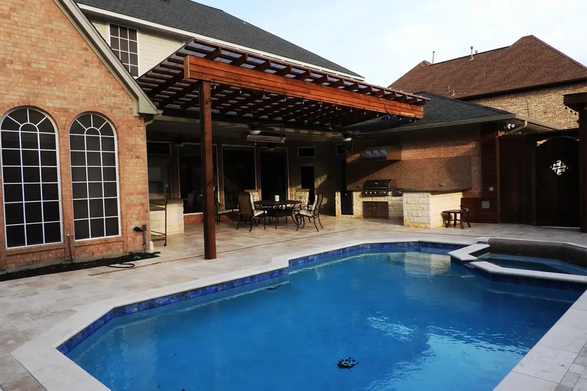 Swimming pool with a pergola, outdoor seating area, and built-in grill in a backyard