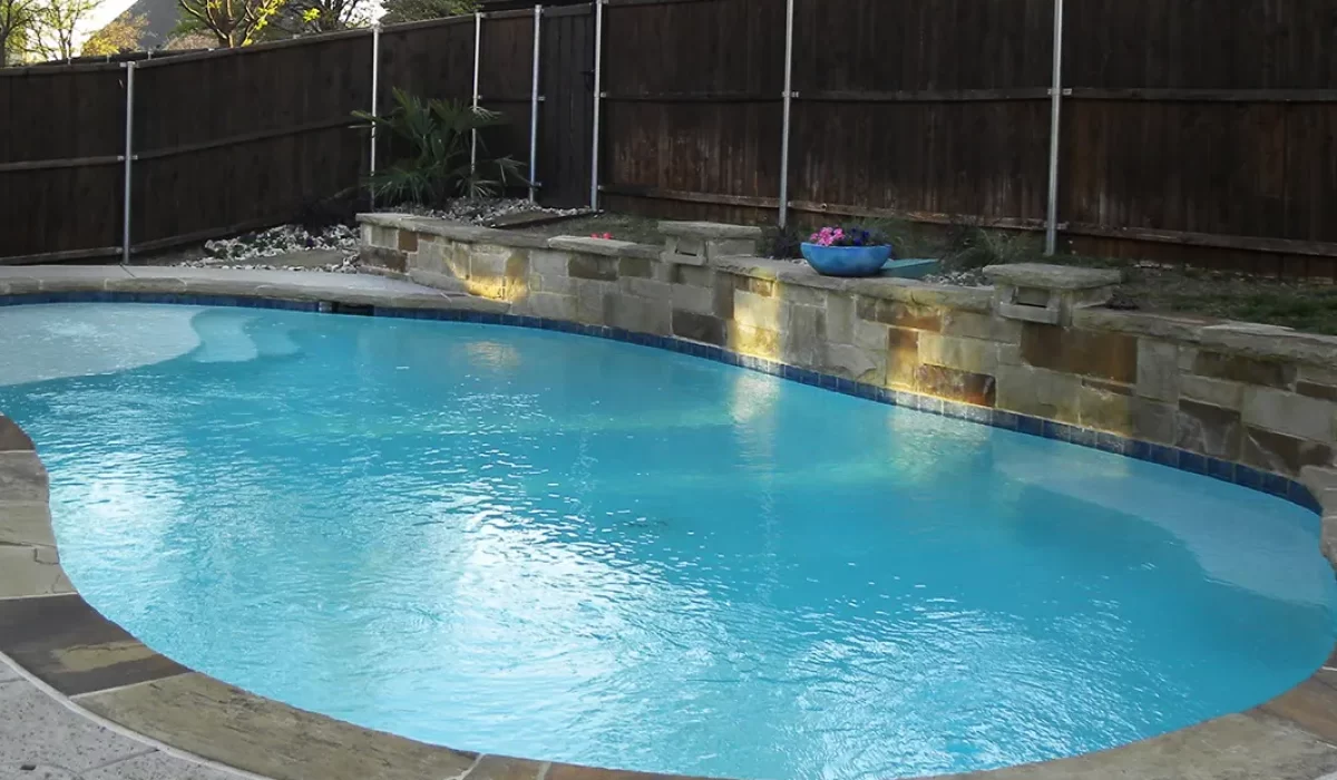Custom pool with stone retaining wall and surrounding landscaping